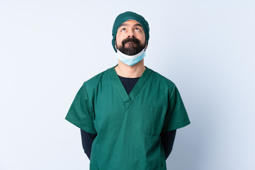 Fototapeta na wymiar Surgeon man in green uniform over isolated background and looking up