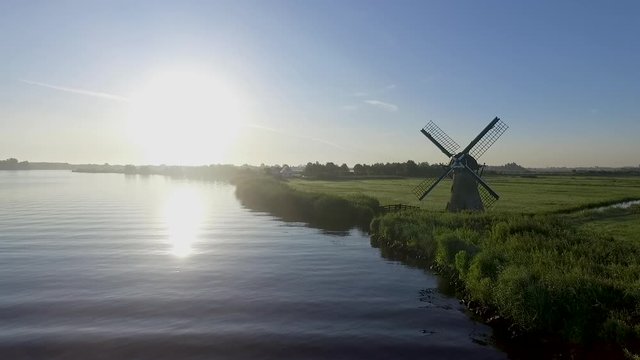 Aerial of a typical dutch meadow in the grasslands with a boat sailing by during a beautiful sunrise