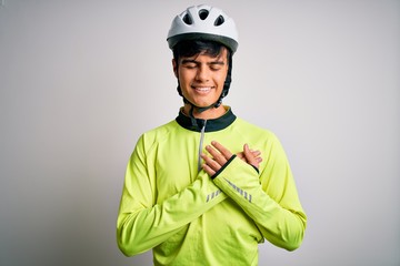 Young handsome cyclist man wearing security bike helmet over isolated white background smiling with hands on chest with closed eyes and grateful gesture on face. Health concept.