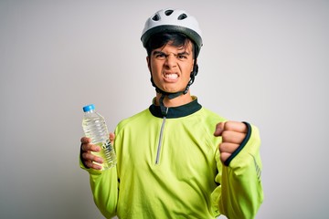 Young handsome cyclist man wearing security bike helmet drinking bottle of water annoyed and frustrated shouting with anger, crazy and yelling with raised hand, anger concept