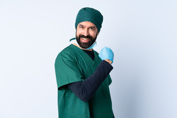 Surgeon man in green uniform over isolated background celebrating a victory