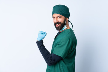 Surgeon man in green uniform over isolated background celebrating a victory