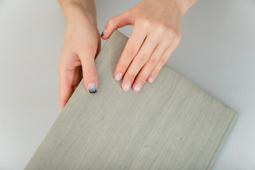 Female hands with fir-tree forest manicure holding leather covered album or notebook on white background. Christmas or winter nail art. Hands care, fingernails design, beauty and health concept.