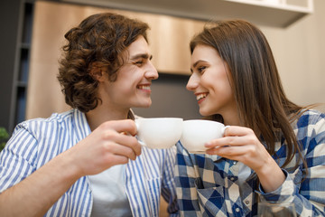 Coffe time at house. Romantic young couple drinking coffee in home kitchen, holding cup