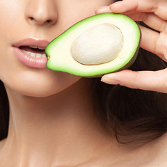 Young beautiful woman holding avocado