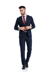 businessman walking while opening jacket and looking aside tough