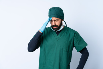 Surgeon man in green uniform over isolated background with headache