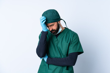 Surgeon man in green uniform over isolated background with headache