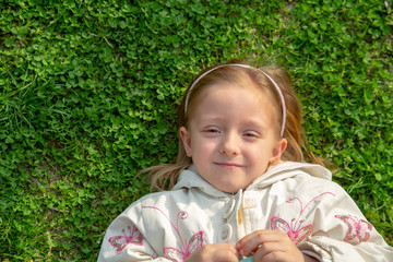 little girl lies on the grass Copy space in left side