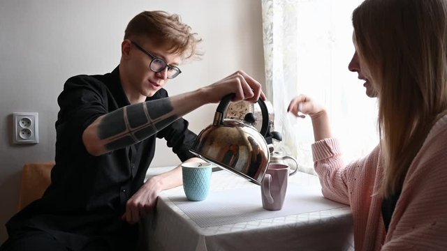 a guy and a girl sit at home in quarantine and drink tea in the kitchen