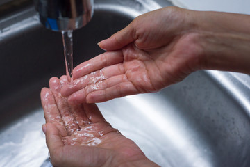 Closeup of handwashing with water at kitchen sink, a prevention measure against Coronavirus