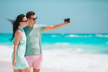 Happy couple taking a photo on white beach on honeymoon holiday