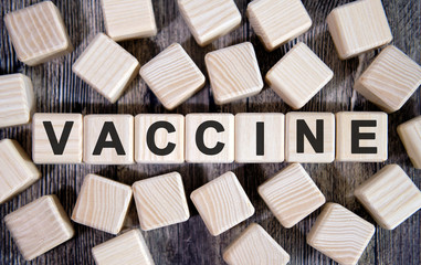 VACCINE - medical concept, text on wooden cubes and many cubes around on a dark background