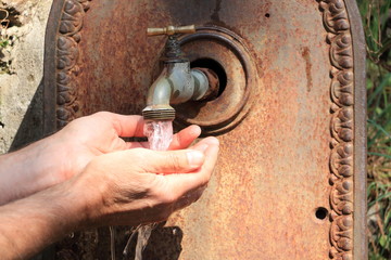 Washing hands under a tap of a public fontaine
