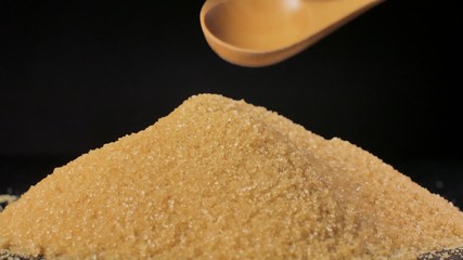 Cane sugar unrefined. A heap of sugar is mixed with a wooden spoon.