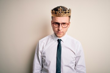 Young handsome caucasian business man wearing golden crown over isolated background skeptic and nervous, frowning upset because of problem. Negative person.
