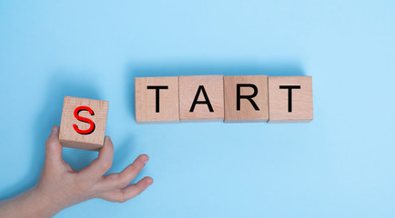 The words START on wooden cubes. Hand arranging wooden blocks with the word START. Start, Start up,...