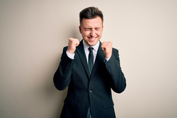 Young handsome business man wearing elegant suit and tie over isolated background excited for success with arms raised and eyes closed celebrating victory smiling. Winner concept.