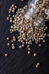 white peppercorns on dark slate stone background