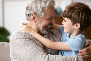 Overjoyed loving elderly grandfather hug cuddle with cute little preschooler grandson, happy caring...