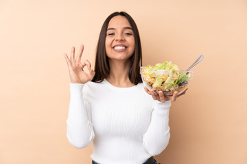 Young brunette girl holding a salad over isolated background in zen pose