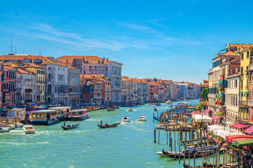 Venice cityscape with Grand Canal waterway. View from Rialto Bridge. Gondolas, boats, vaporettos docked and sailing Canal Grande. Venetian architecture colorful buildings. Veneto Region, Italy.