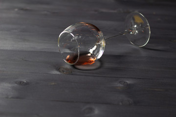 Laying glass with pink wine on black wooden background