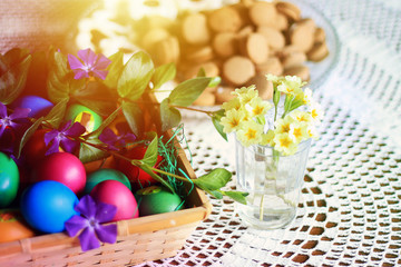 Easter colorful eggs, flowers and greens, white tea-set with eggs inside the cups with butterflies thin porcelain, on a white rounded knitted tablecloth. Country cozy style - happy holiday!