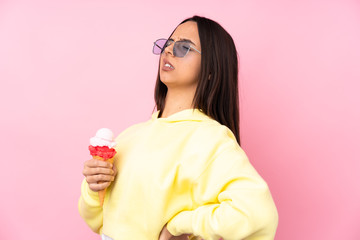 Young brunette girl holding a cornet ice cream over isolated pink background suffering from backache for having made an effort