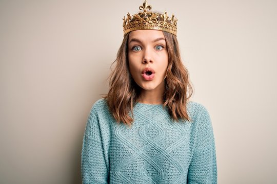 Young blonde girl wearing queen golden crown over isolated background afraid and shocked with surprise expression, fear and excited face.