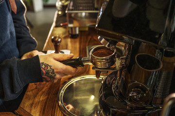 Barista making coffee grinding freshly roasted coffee beans in cafe, close up photo