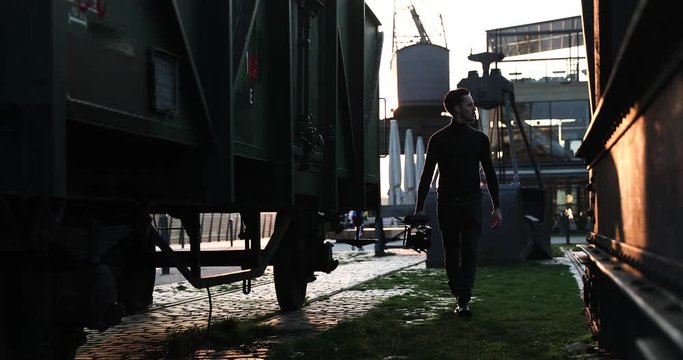 Male filmmaker walk with the camera on sunset in a big city. Industrial