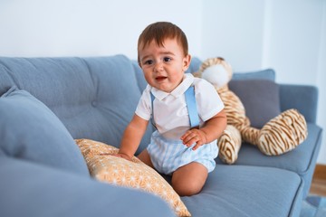 Adorable toddler sitting on the sofa crying at home