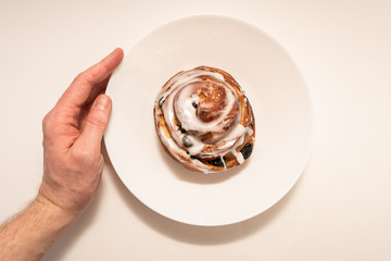 bun with raisins in white plate on white background