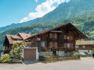 Beautiful traditional wooden house in the alpine village, Switzerland. House decorated with flowers, near flowerbed