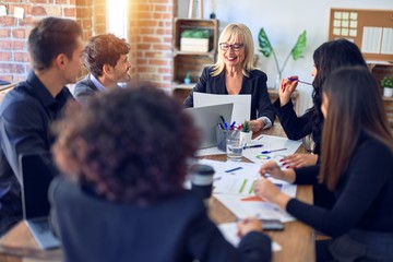 Group of business workers smiling happy and confident. Working together with smile on face  using laptop and speaking at the office