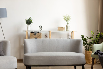Comfortable grey sofa on wooden heated floor, empty modern living room with contemporary interior...