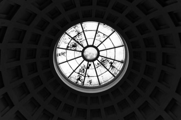 A view from inside the building onto a dome with caissons, which ends with a round window