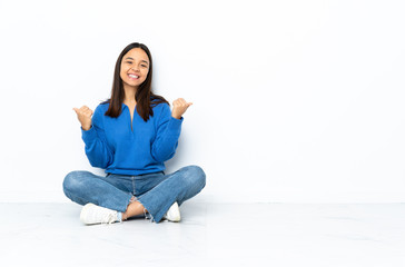 Fototapeta na wymiar Young mixed race woman sitting on the floor isolated on white background with thumbs up gesture and smiling