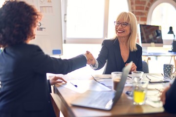 Group of beautiful bussineswomen smiling happy. Working together shaking hands for agreement at the office