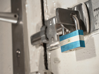 A bolted door secured by a padlock with the national flag of Nicaragua on it.(series)