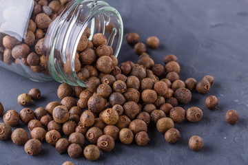 fresh spicy peppers allspice on a dark stone background
