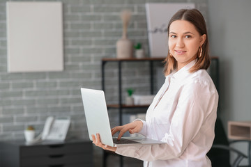 Portrait of young businesswoman with laptop in office