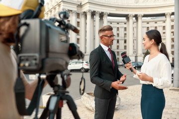 Journalism that is independent, honest, and dignified. Cameraman and news reporter interviewing...