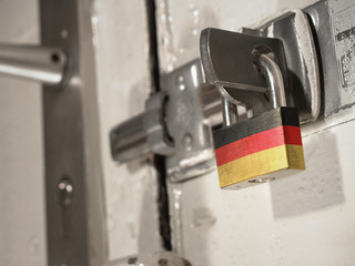 A bolted door secured by a padlock with the national flag of Germany on it.(series)