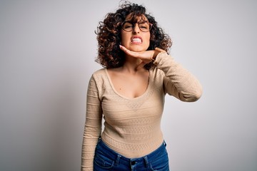 Young beautiful curly arab woman wearing casual t-shirt and glasses over white background cutting...