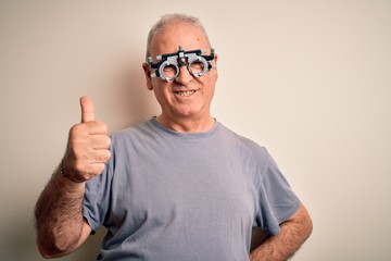 Naklejka premium Middle age hoary man controlling vision wearing optometry glasses over white background doing happy thumbs up gesture with hand. Approving expression looking at the camera showing success.