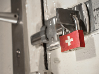 A bolted door secured by a padlock with the national flag of Switzerland on it.(series)