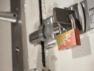A bolted door secured by a padlock with the national flag of Bhutan on it.(series)