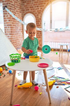 Adorable Blond Toddler Playing With Plastic Food Around Lots Of Toys At Kindergarten